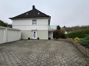 a white house with a black roof and a driveway at Ferienwohnung Sylt in Meinerzhagen