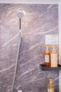 a shower head on a wall with two bottles on a shelf at shinjuku lions house newly renovated, elevator, washmachine,kitchen in Tokyo