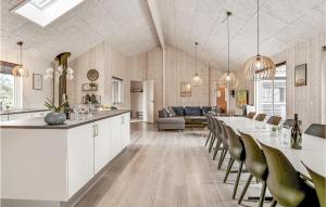a kitchen and living room with a long table and chairs at Beautiful Home In Idestrup With Sauna in Marielyst