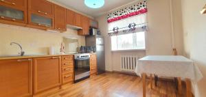 eine Küche mit Holzschränken und einem Tisch darin in der Unterkunft 2-х комнатная квартира в центре in Qaraghandy