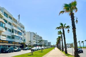 eine Straße mit Palmen und Autos auf der Straße in der Unterkunft N4, À Rabat, premium séjour face à La Corniche in Rabat