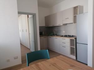 a kitchen with white cabinets and a blue chair at Appartamento Delfino Blu in Porto Torres +13 photos