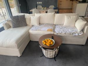 a white couch with a bowl of oranges on a table at County House - Ingarö in Ingarö