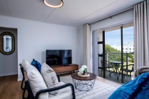 Una sala de estar con un sofá y un televisor. en Two-bed Apartment on Big Bay Beach Club,Cape Town, en Ciudad del Cabo