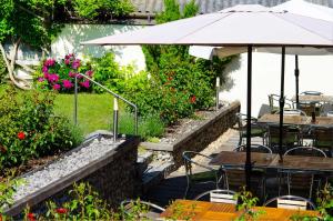 a patio with tables and an umbrella and flowers at Weingut Stadler in Falkenstein