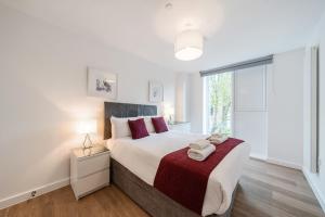 Un dormitorio con una cama grande y una ventana grande. en Roomspace Serviced Apartments - Walton Court, en Hersham