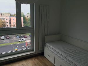 ワルシャワにあるModern & Functional Apartment Wwaのベッド1台、通りの景色を望む窓2つが備わる客室です。