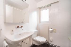 un bagno bianco con lavandino e WC di Seeblick Höhenhotel a Emmetten