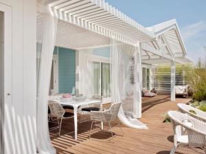 a white pergola on a deck with a table and chairs at Cabana com Arte na Comporta in Grândola