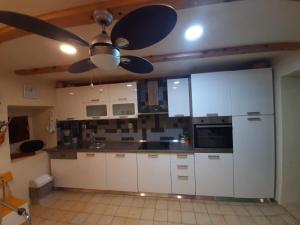 eine Küche mit weißen Schränken und einem Deckenventilator in der Unterkunft Katia in Grižane