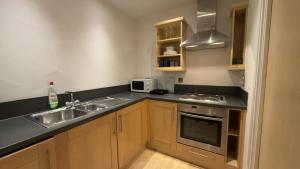 a kitchen with a sink and a microwave at Modern spacious Studio opposite station II in London +11 photos