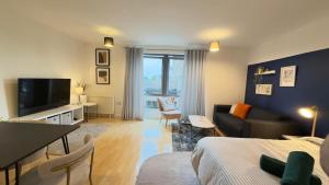 a living room with a bed a couch and a tv at Modern spacious Studio opposite station II in London