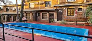 a man standing next to a swimming pool in front of a house at Iguazú Green Hotel in Puerto Iguazú