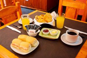 a table with a breakfast of sandwiches and eggs and coffee at Iguazú Green Hotel in Puerto Iguazú