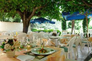 a group of tables with white chairs and a tree at Logis Hotel Des Voyageurs Restaurant La Bonne Tabl'Hay in Livron-sur-Drôme