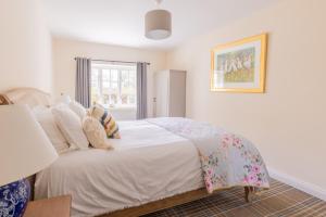 Un dormitorio con una cama con sábanas blancas y una ventana. en Keepers Cottage - North East Escapes, en Stocksfield