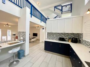 a large kitchen with white cabinets and blue stairs at Dolphinbeach Seafront Villa in Langstrand