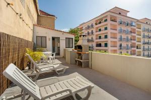 a balcony with chairs and a table and a building at Host Albina in Funchal