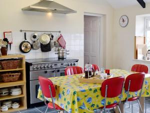 una cucina con tavolo e sedie rosse intorno di Glendale Cottage a Haltwhistle
