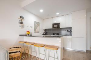 Una cocina con gabinetes blancos y taburetes de bar. en El Balconcito, en Torre del Mar