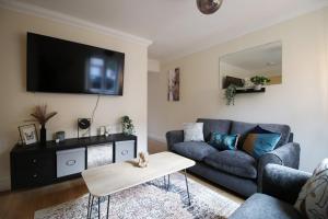 a living room with a couch and a tv on the wall at Alicia's Way by Tŷ SA in Newport