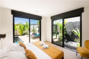 a bedroom with a large bed and large windows at Lagon Paradis - 6 Villas individuelles avec Piscine ou Jacuzzi - Loc Voiture Cabriolet ou SUV in Le Gosier
