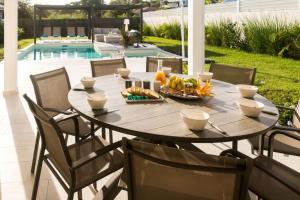 a dining table and chairs with a table and a pool at Lagon Paradis - 6 Villas individuelles avec Piscine ou Jacuzzi - Loc Voiture Cabriolet ou SUV in Le Gosier