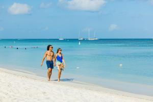 a man and a woman walking on the beach at TRYP by Wyndham Aruba in Palm-Eagle Beach
