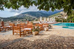 a group of wooden benches next to a swimming pool at Apart-Hotel Llazari in Himare