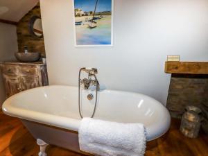 un bagno con vasca e un dipinto sul muro di Crab Cottage a Delabole Altre 23 foto