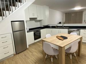 a kitchen with a wooden table and white cabinets at Singer's Lounge in Porto de Mós