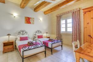 a bedroom with two beds and a desk and a window at Villagg tal-Fanal in Għasri +37 photos