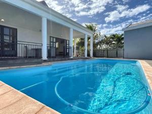a large blue swimming pool in front of a house at N'joy Pereybere Villa in Pereybere +36 photos