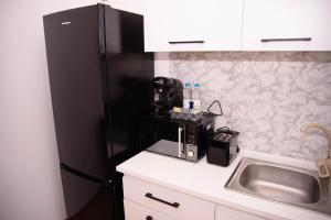 a kitchen with a sink and a black refrigerator at Lisia Residence #1 in Piatra Neamţ