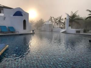 a resort swimming pool with the sun setting in the background at The Oia Pai Resort in Pai +38 photos