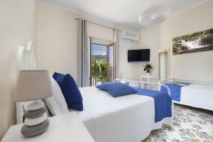 a white bedroom with two beds and a window at Casa Lucy in Sorrento