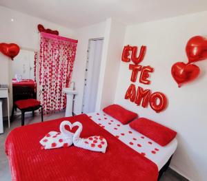 a bedroom with a red bed with hearts on the wall at Praia dos Anjos Suítes in Arraial do Cabo