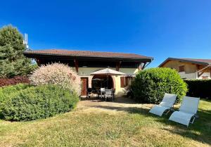 dom z dwoma krzesłami i parasolem na dziedzińcu w obiekcie La Charmelle - Belle maison avec jardin & terrasse w mieście Corcieux