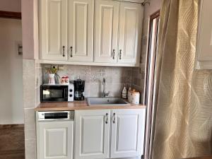 a kitchen with white cabinets and a sink and a microwave at Lydias House in Arachova