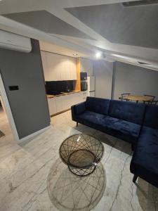 a living room with a blue couch and a glass table at Apartament w Centrum z Jacuzzi, prywatny parking, klimatyzacja 4 in Radom +2 photos