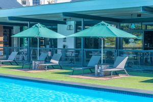 a group of chairs and umbrellas next to a pool at Exquisite Getaway - Luxury Apartment in Sandown