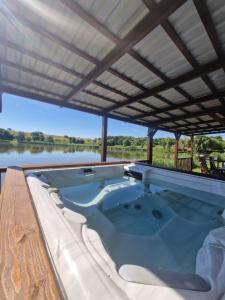 a hot tub under a roof with a view of a lake at Vízivilág Vendégház és Halastó in Nagyvázsony