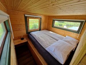 a small bed in a wooden room with a window at Vízivilág Vendégház és Halastó in Nagyvázsony
