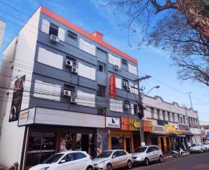 a building with cars parked in front of it on a street at Hotel Ideal in Chapecó