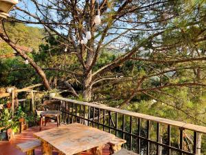a wooden table and bench on a deck with a tree at Nhà Chạng Vạng in Ấp Ða Lợi