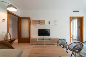 un soggiorno con televisione, tavolo e sedie di WELCS APARTAMENTO 189 PDA con piscina comunitaria a S'Agaró