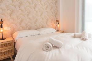 2 letti bianchi in una camera da letto con carta da parati di WELCS APARTAMENTO 189 PDA con piscina comunitaria a S'Agaró Altre 27 foto