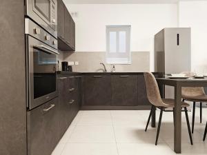 a kitchen with brown cabinets and a table with chairs at Blue Pearl in Żurrieq