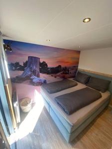 una camera da letto con un letto e un dipinto sul muro di Prachtig Boschalet met CV, Airco en Sauna op de Veluwe a Doornspijk
