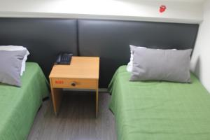 a room with two beds and a table with a night stand at Guest House Porto Clerigus in Porto
